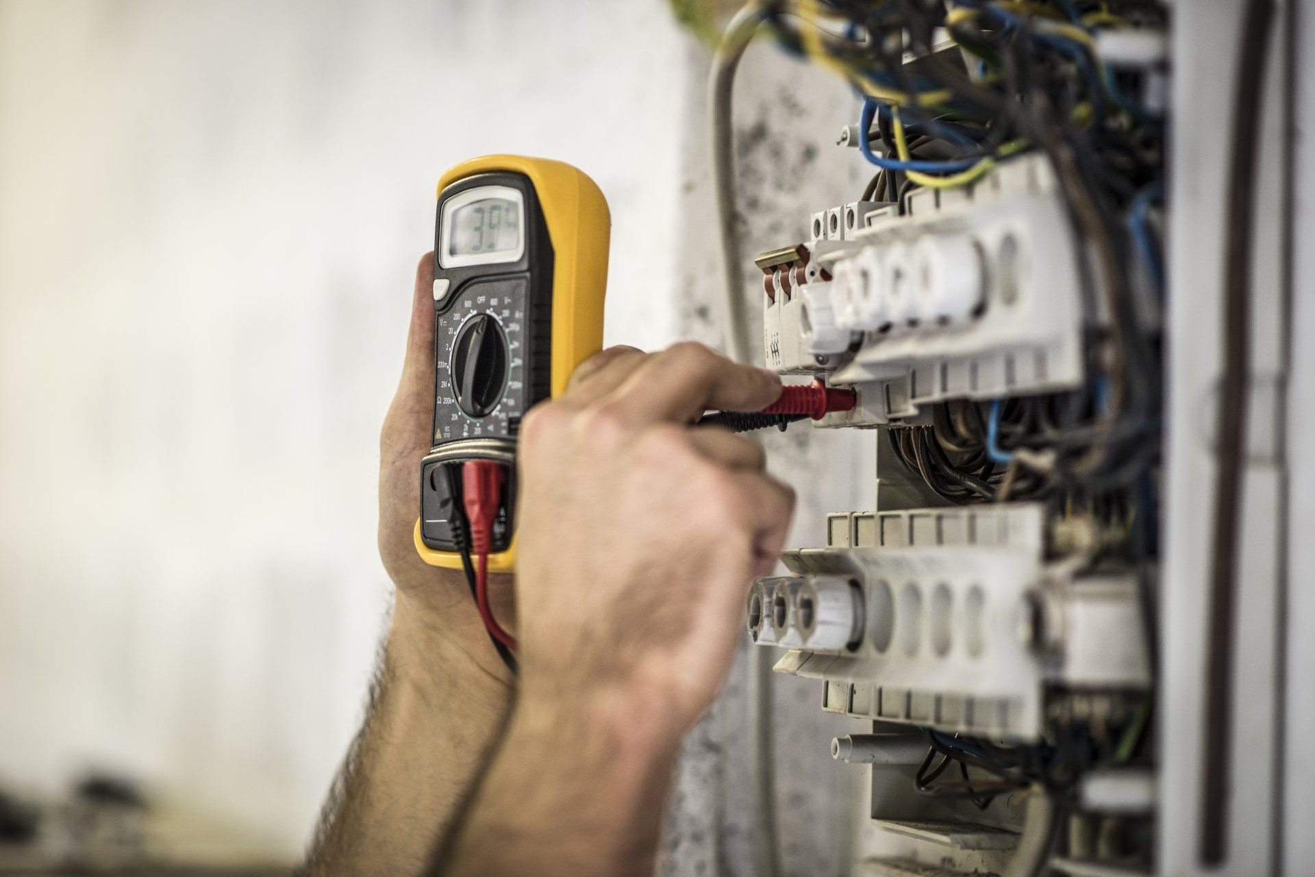 Électricien mesurant la tension d’un tableau électrique avec un multimètre